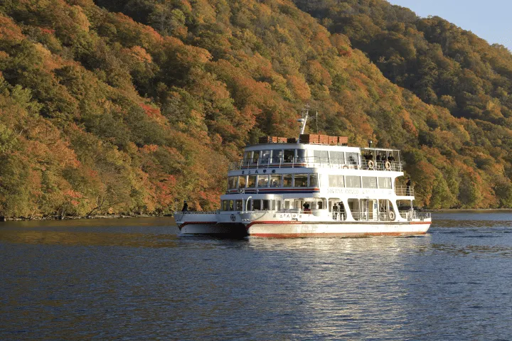 紅葉の山を背に十和田湖を進む遊覧船